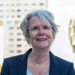 Portretfoto van Dineke Smit, met een iconisch gebouw in Almere op de achtergrond